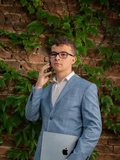 Dorian Drgonec w garniturze rozmawia przez telefon i trzyma MacBooka, jak zupełnie normalny, poważny CEO